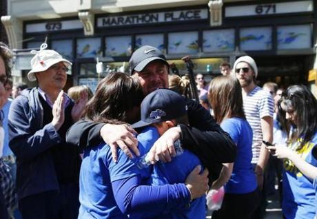 Paul Strong (center) shares an emotional embrace with his wife, Shannon (left) and son, Colin, 12, all of Wakefield, during a moment of silence in front of Marathon Sports.
